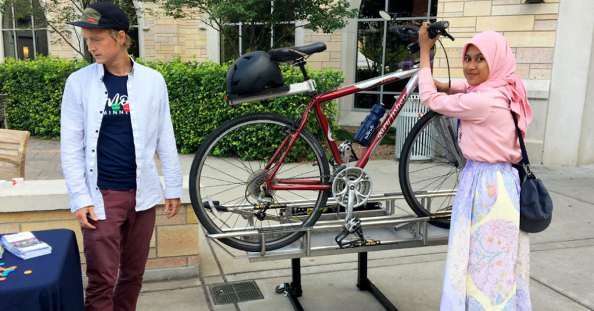 Woman at the University of St. Thomas learning how to put a bike on Metro Transit bus rack