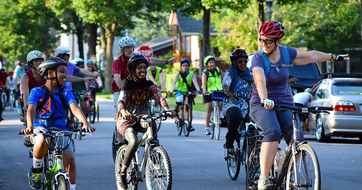 Adults and kids smiling and biking together on a Slow Roll bike ride in Saint Paul