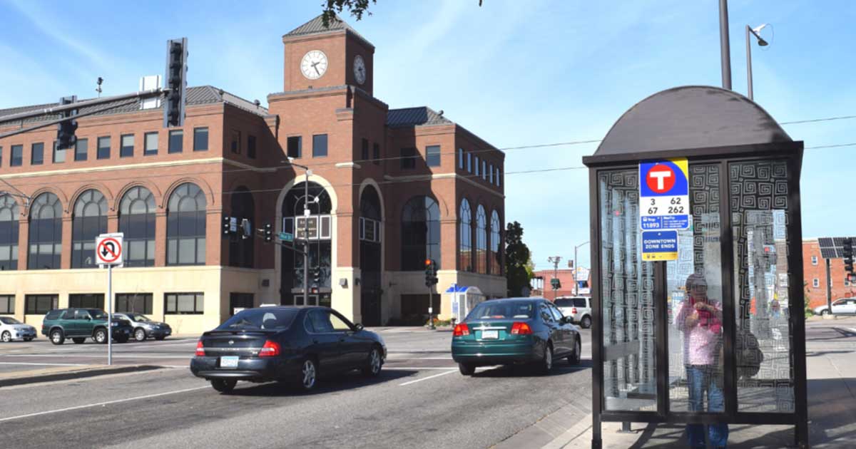Saint Paul Rice Street Capitol Area intersection. Cars on the road and woman on sidewalk waiting for the bus,