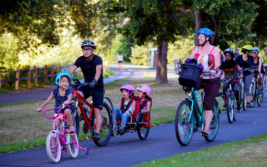 Adults and children biking together on an off-street trail in Saint Paul during a Move Minnesota community bike ride.