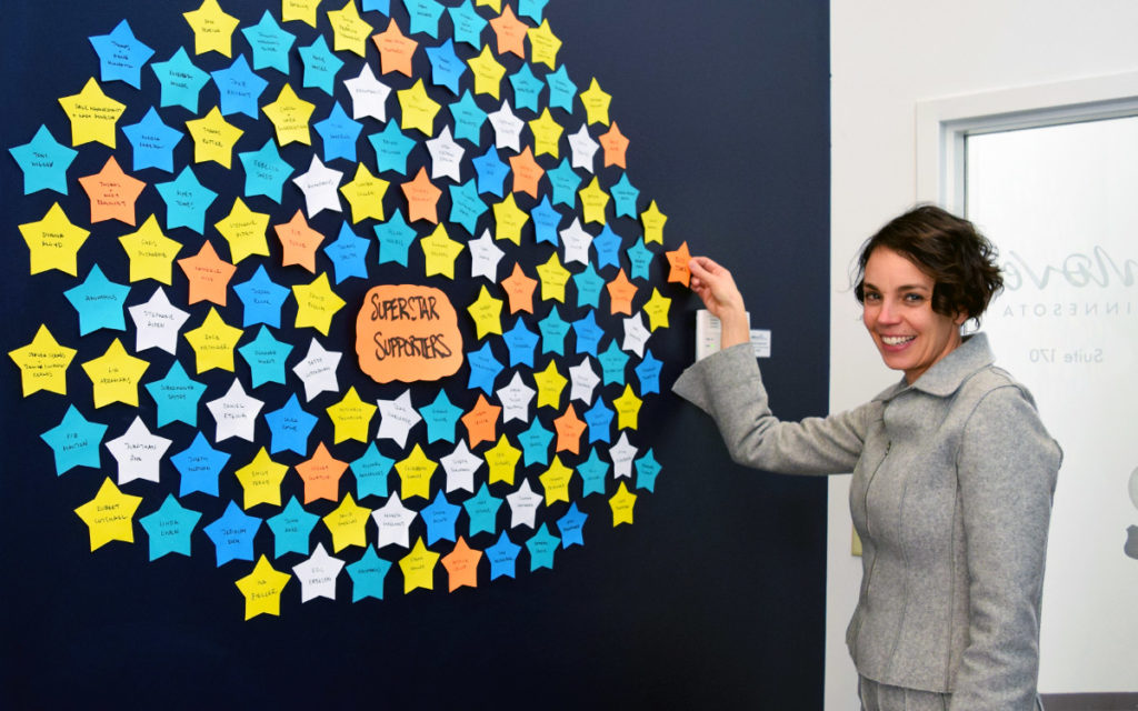 Move Minnesota Executive Director, Jessica Treat, placing a paper star with a donor's name onto a wall full of stars for the board alumni challenge