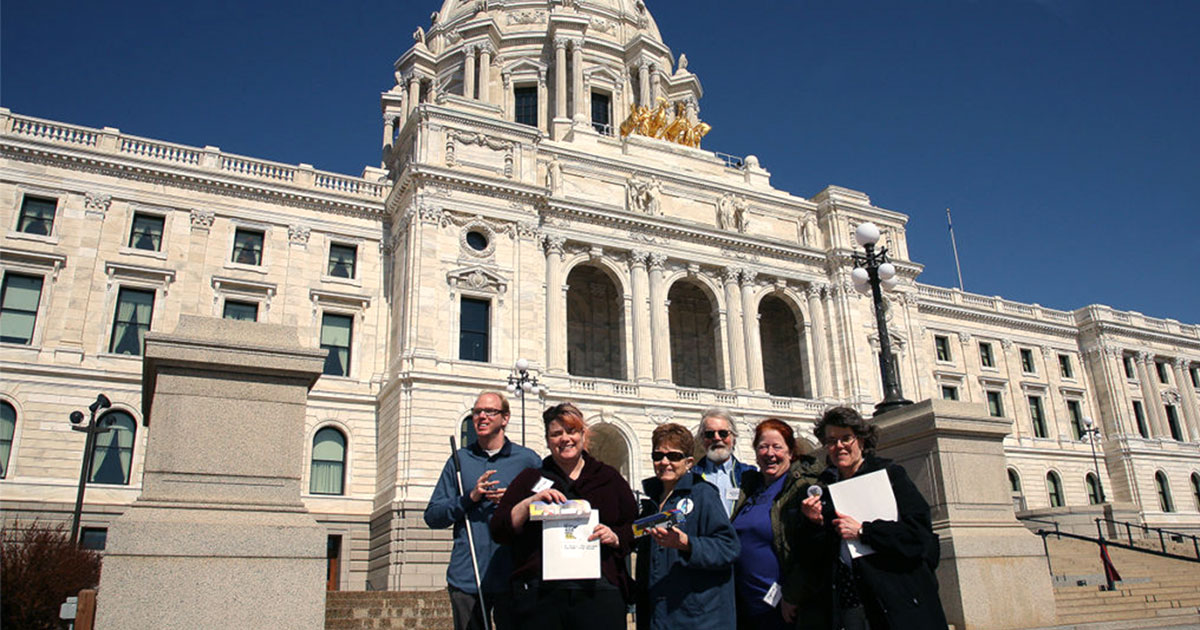 Transit advocates smiling and posing in front of the State Capitol