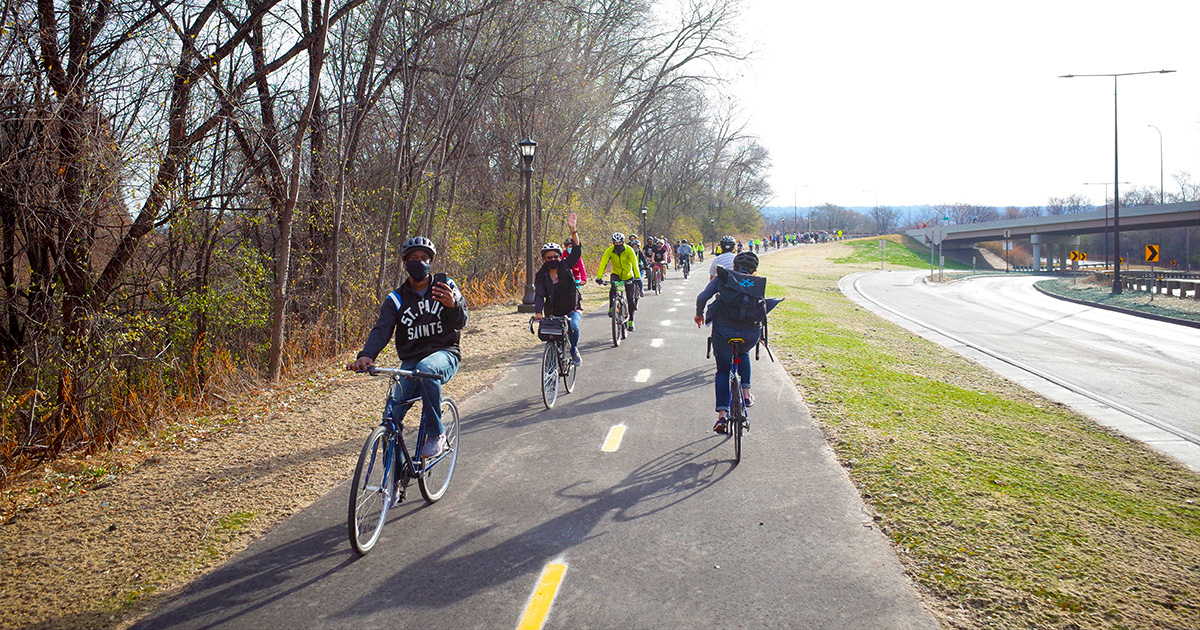 Many people biking on Saint Paul's new Ayd Mill Trail on opening day. The photo also shows the trail is fully separated from the road next to it.