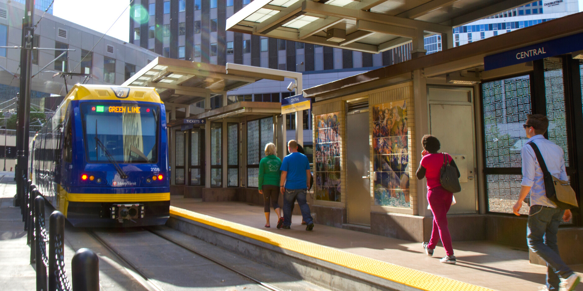 A green line train approaching the central station platform in Saint Paul