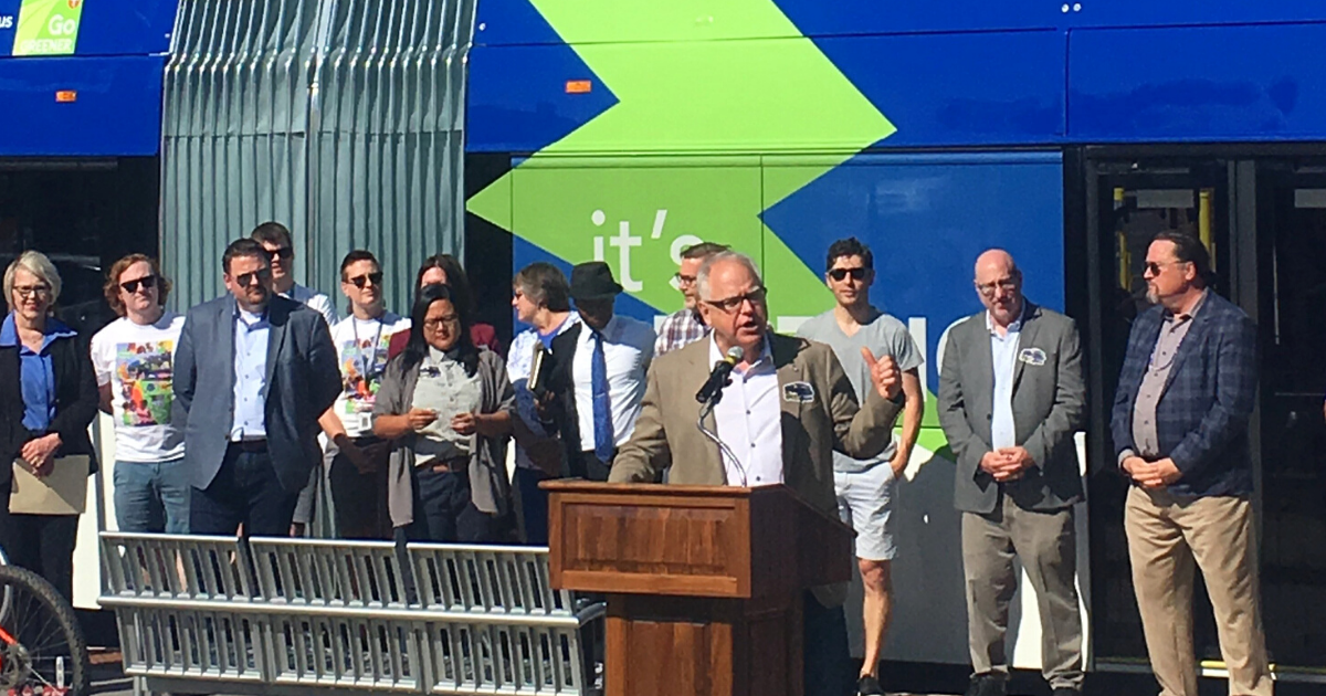 Governor Walz speaking behind a podium addressing crowd at C Line grand opening in Minneapolis.