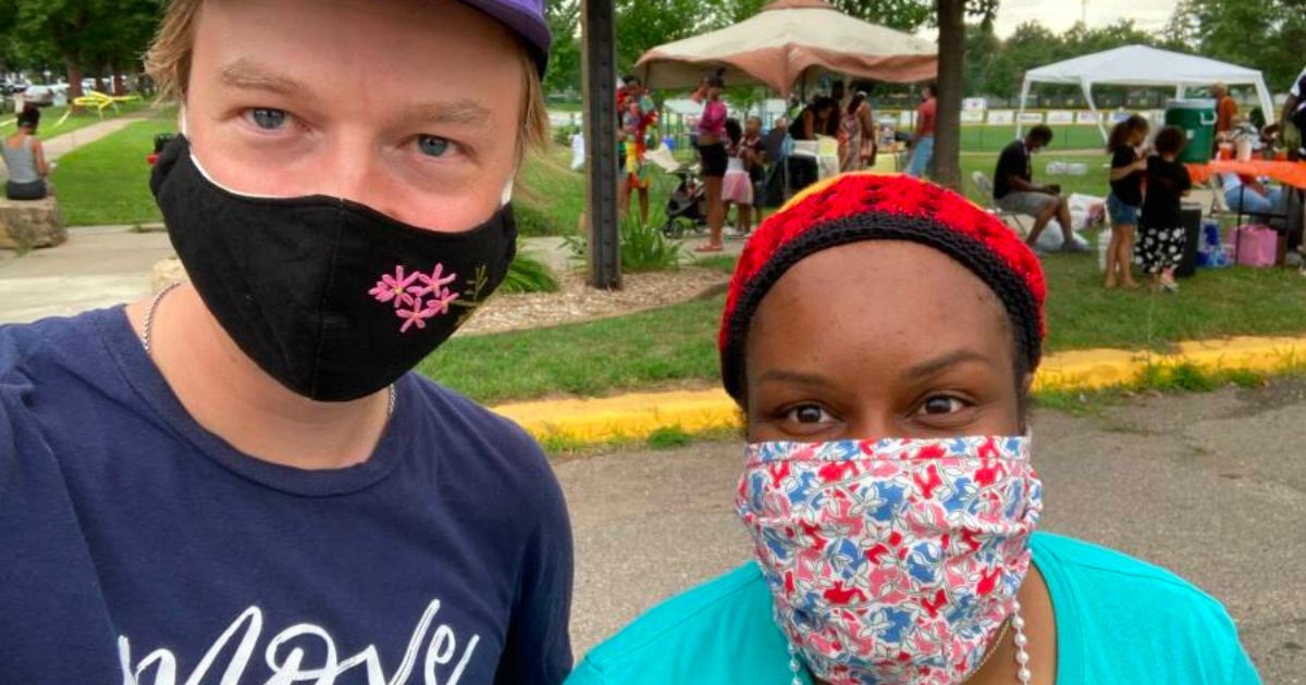 Two Move Minnesota staff members posing for a selfie in front of a community food event in Saint Paul.