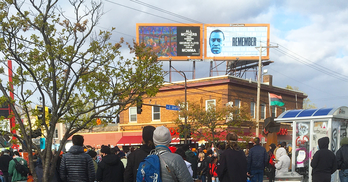 A crowd gathered at George Floyd Square in Minneapolis with billboard messages dedicated to George.