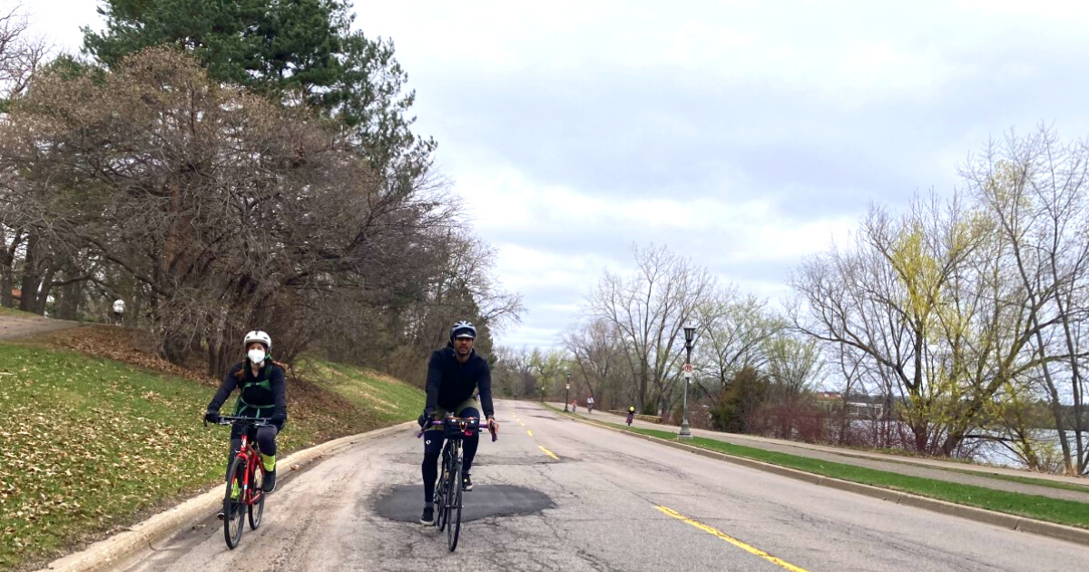 Two people riding their bikes on street in Saint Paul.