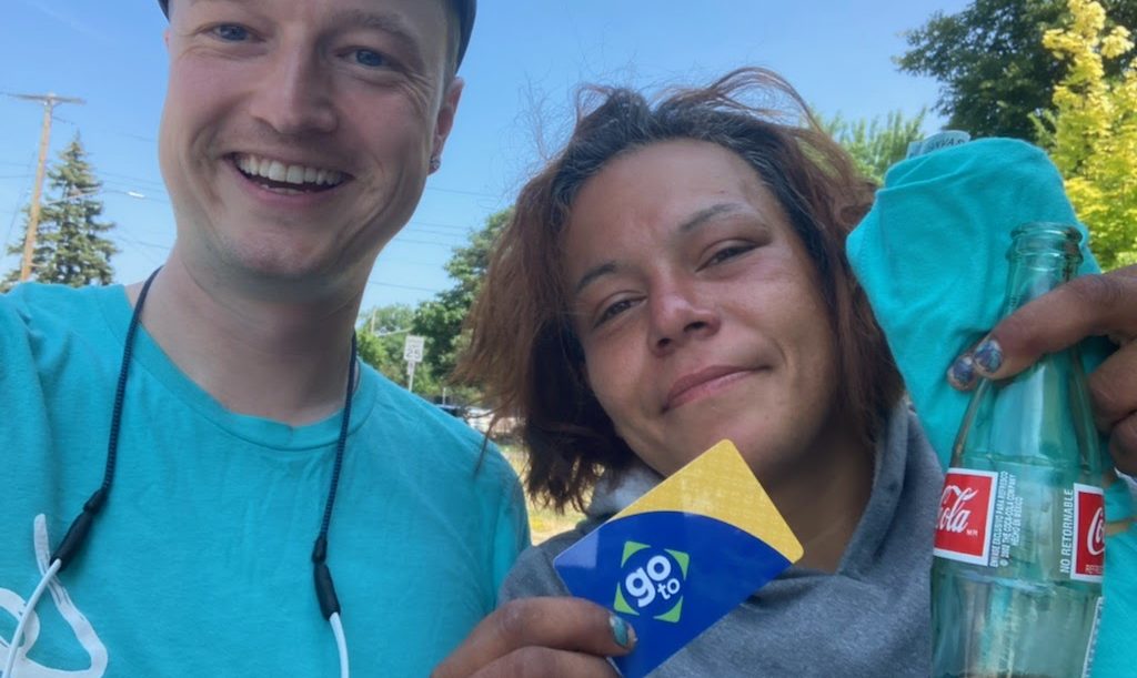 Move Minnesota staff doing outreach along the C Line is pictured with a transit rider holding a Go-To card.