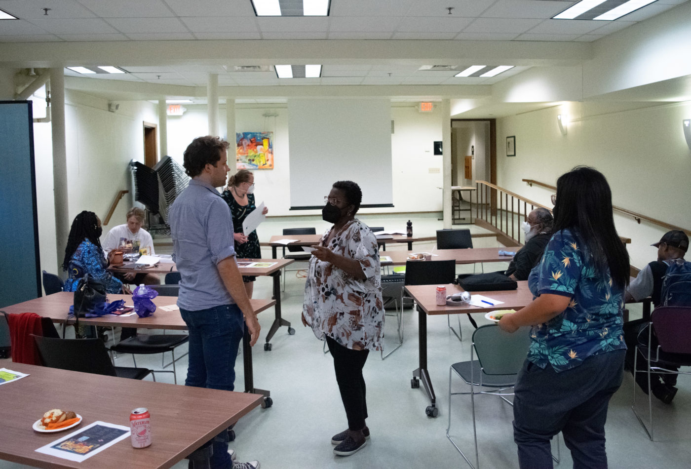 group of people having several small conversations in a room with tables