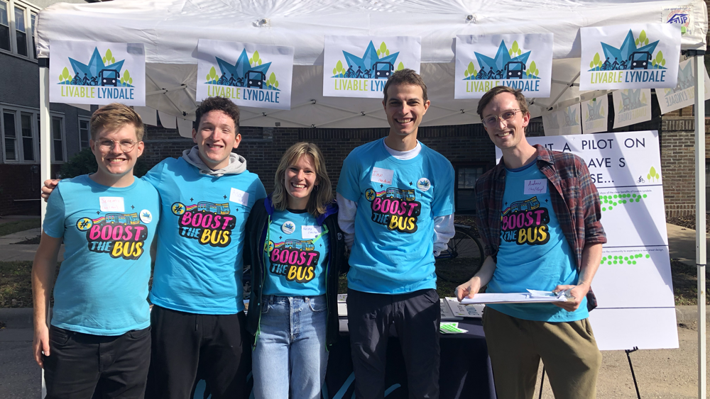 A group of Minneapolis volunteers at a Move Minnesota table decorated with the vibrant blue Livable Lyndale logos at the Open Streets event