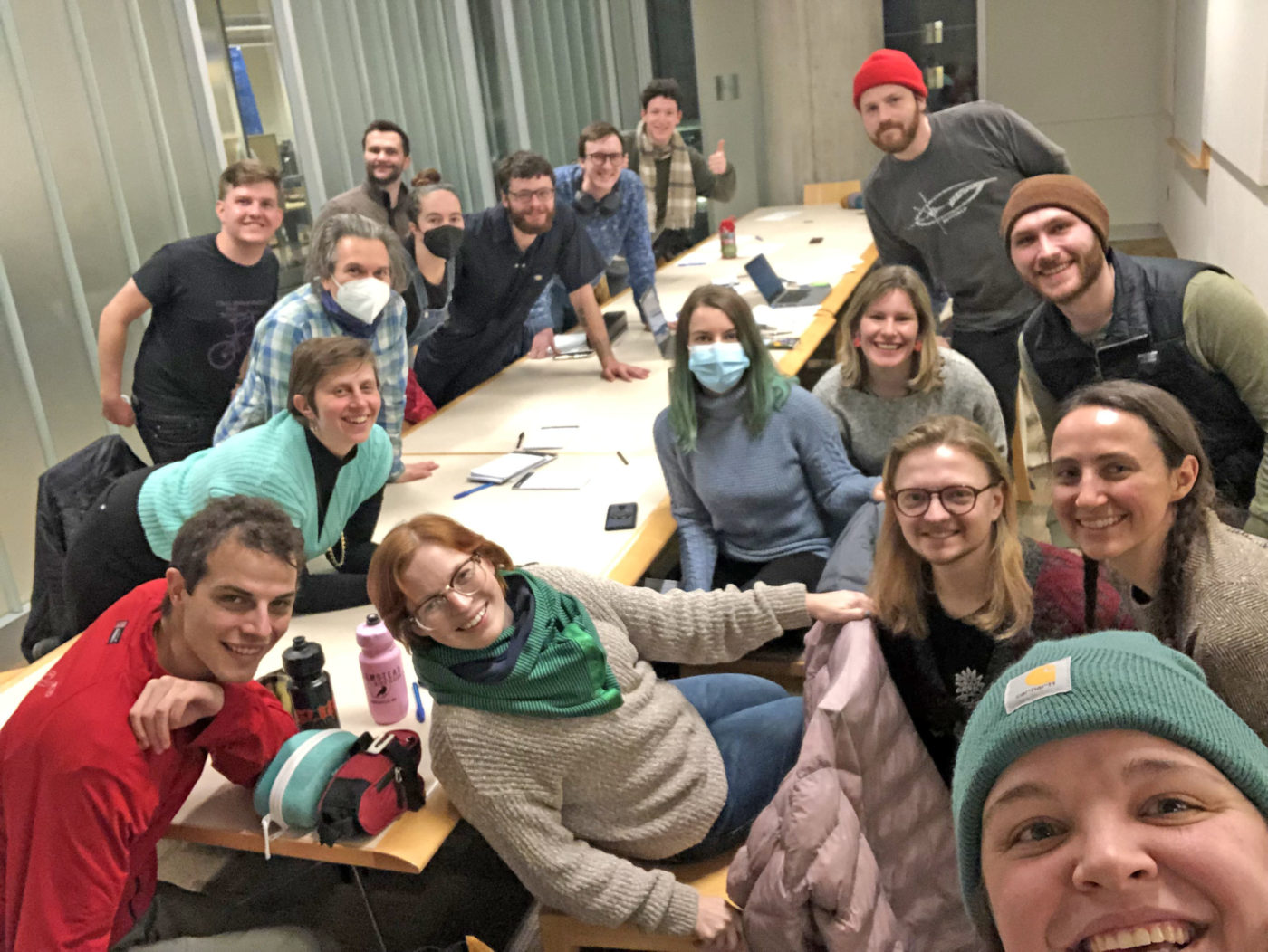 A group of smiling volunteers posing for a group selfie at a long table at the library after a Minneapolis Volunteer Team meeting 