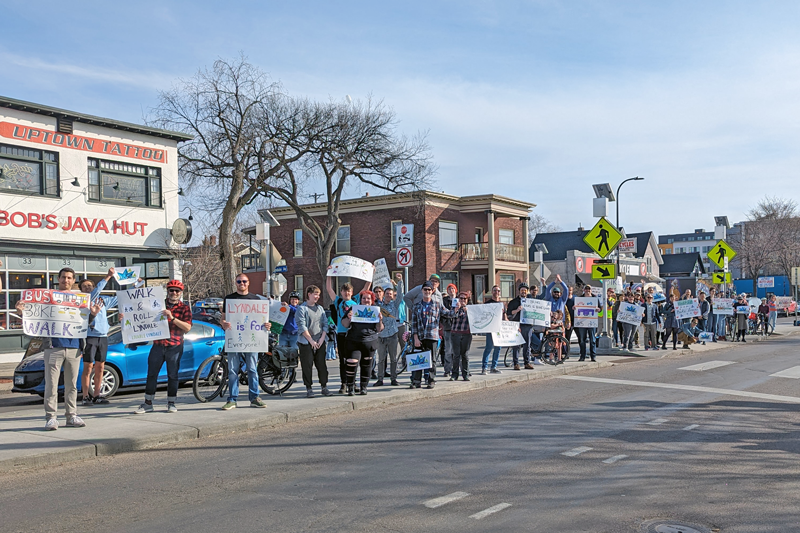 Close to 50 community members rallying in the median at 27th and Lyndale in Minneapolis, holding signs in favor of walking, biking, rolling and riding the bus on Lyndale Avenue 