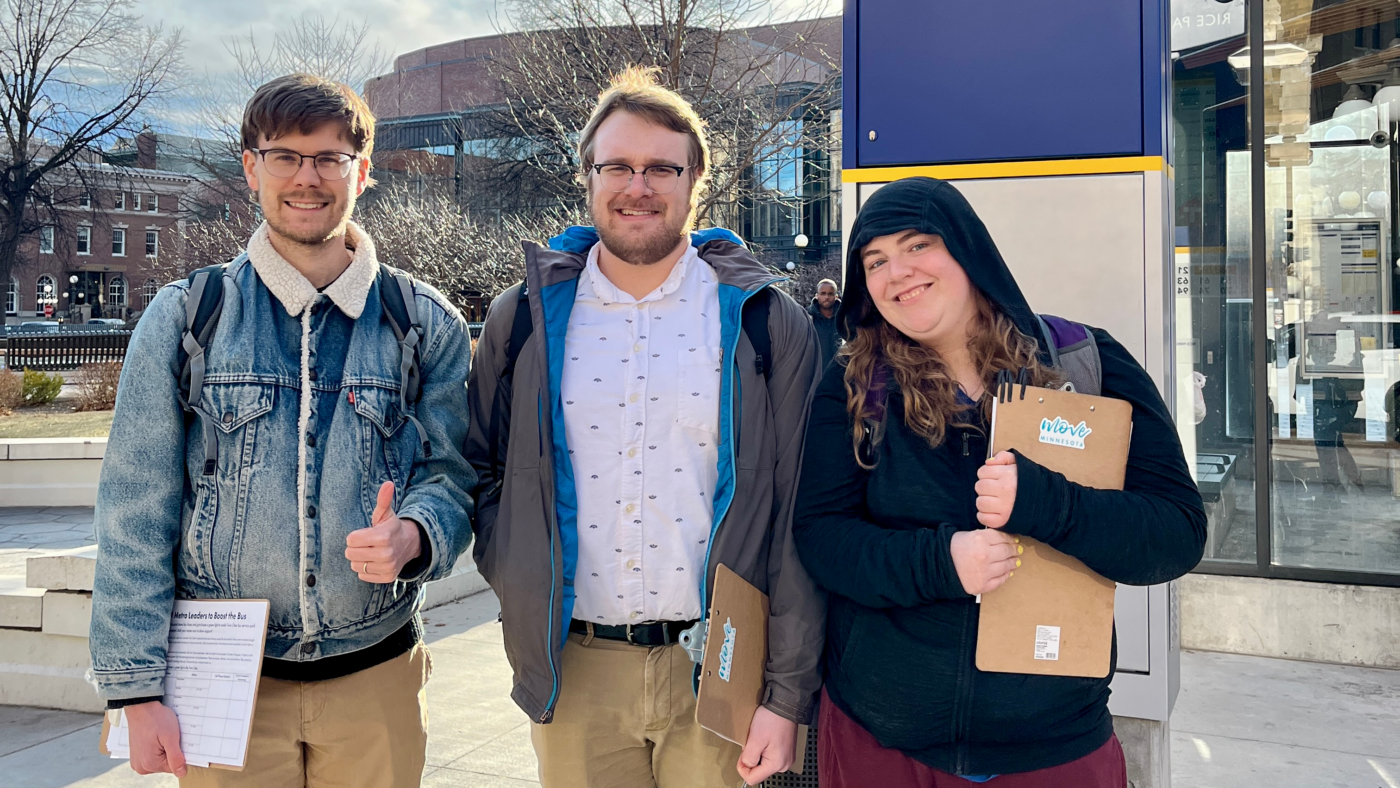 Three smiling volunteers get ready to canvass riders on the bus!