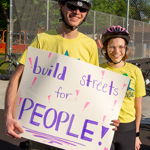 People holding a sign that reads build streets for people!